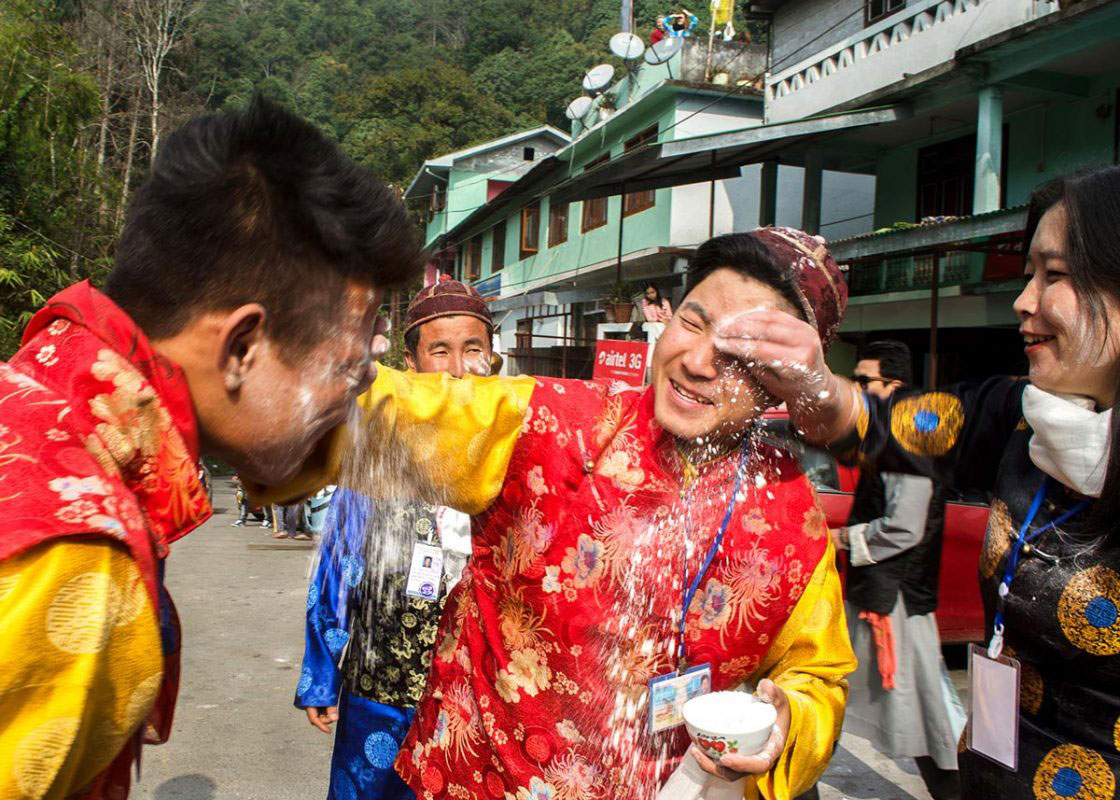 Sikkim, India- December 2015. Group of traditionally dressed "Bhutia" performer is celebrating "Lawsung" by throw paddy flour to each other in front of Rumtek Monastery. Lawsung is a five day's festival to offering thanks to God for good harvest, as well as this is the festival to welcome Tibetan upcoming year.