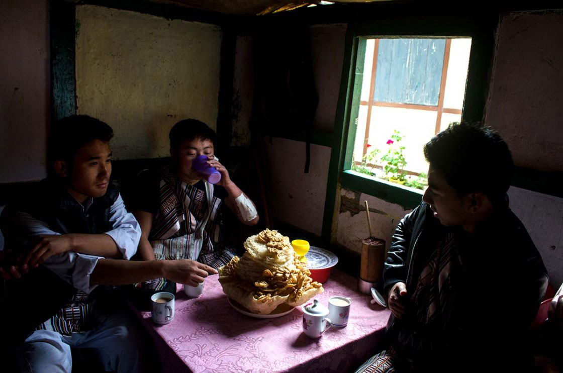 Sikkim, India- December 2015. Group of traditionally dressed "Lepcha" performer is having home made sweet snacks "Zeroo", "Kabje", "Paumulangcho" and home made wine, "Chi" at a Lepcha house of Sahri Kopibari Village, just before "Namsung" special performance. Namsung is a five day's festival celebrated by Lepcha community to offering thanks to God for good harvest, as well as this is the festival to welcome Tibetan upcoming year.